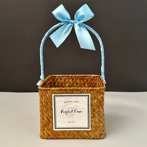 Close-up of a handmade square woven straw gift basket with an elegant light blue ribbon