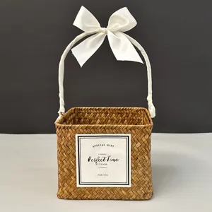 Hand-woven square straw gift basket with handle and elegant white satin ribbon bow