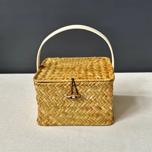 Détail d'une boîte cadeau carrée en paille tressée avec couvercle à cabillot et anse