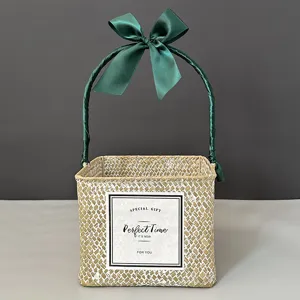Detailed view of a square handwoven straw gift basket decorated with a green ribbon bow