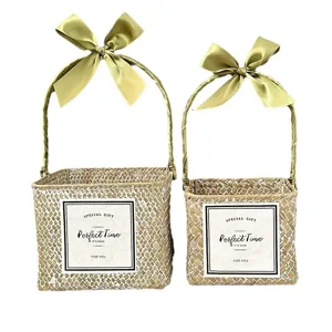 Two-piece set of square woven straw gift baskets decorated with olive green ribbons