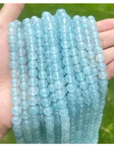 Vista detallada de cuentas de calcedonia azul claro translúcidas para joyería DIY.