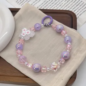 Detailed macro view of a colorful beaded phone charm with purple pearls and pink crystals