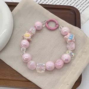 Detailed view of handmade pink beaded phone charm with star and doughnut motifs