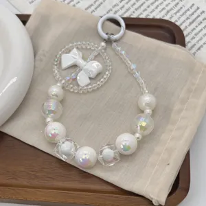 Close-up of iridescent beaded phone charm featuring white bow and doughnut ring element