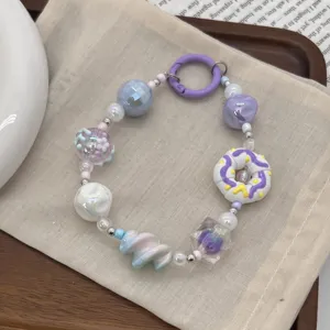 Detailed view of hand-painted donut and purple iridescent beads on a phone charm