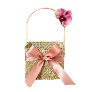 Handmade woven seagrass gift basket with pink ribbon bow and orchid flower for wedding candy.