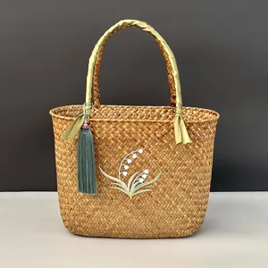 Vue détaillée du panier en jonc de mer tissé à la main avec broderie florale et gland.