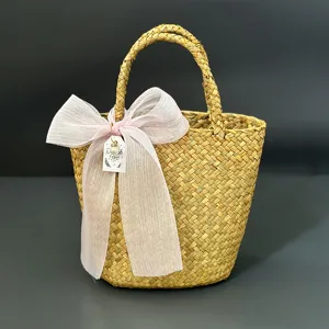 Handmade woven straw basket detail with pink organza bow and hanging tag for rustic gift packing.