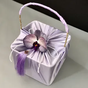 Elegant purple satin gift box with orchid and tassel handle for weddings, parties and favors.
