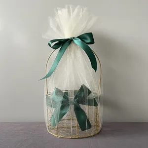 Gold wire gift basket with white tulle and green bow for wedding, party, and holiday packaging detail view.