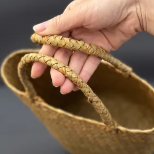 Close up of woven straw basket handle, natural material, detailed braided design, texture.