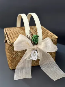 Gros plan d'un panier cadeau en paille tressée à la main avec un nœud élégant et poignée.