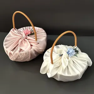 Detailansicht eleganter handgeflochtener Geschenkkörbe mit Satinhülle und Blumen