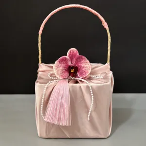 Pink satin gift box detail view featuring orchid flower pearl string and tassel design for wedding.