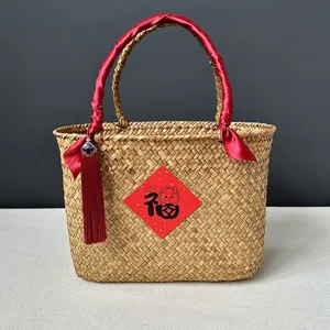 Panier cadeau en jonc de mer avec ruban rouge et pompon, idéal pour l'emballage de festival.