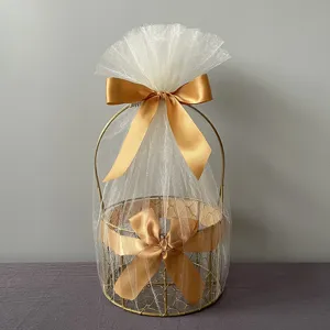 Gold metal gift basket wrapped in white tulle with satin bows, ideal for event packing.