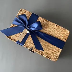 Boîte de rangement tissée à la main en détail, rotin naturel avec ruban nœud bleu marine.