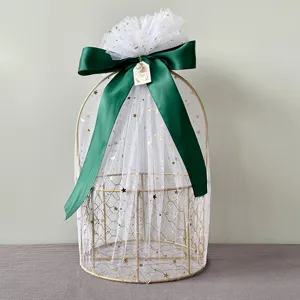 Gold wire gift basket detail featuring white star tulle and elegant dark green satin ribbon bow.
