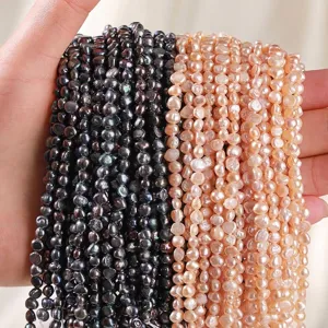 Hand holding strands of natural pink and black freshwater pearls for jewelry making DIY