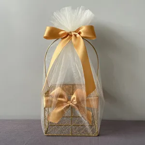 Detail shot of a golden wire gift basket wrapped in sheer white tulle with elegant gold satin ribbons.
