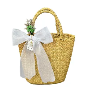 Handmade woven straw gift basket featuring a white organza bow and dried flower decor.
