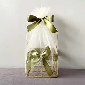 Gold wire gift basket decorated with white tulle and olive green bows for party packaging.