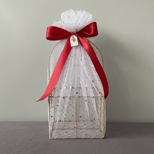 Gold wire mesh gift basket detail, decorated with white starry tulle and red satin bow.