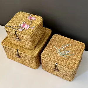 Detail of hand-woven straw gift boxes with exquisite floral embroidery and toggle lids.