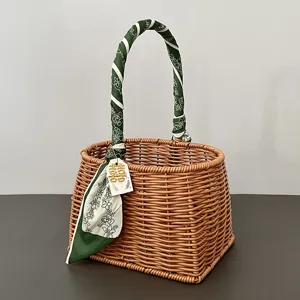 Gevlochten rotan mand met groene bloemensjaal en geluksetiket, ideaal voor huwelijkscadeaus.