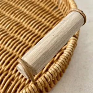 Dettaglio ravvicinato del vassoio in rattan intrecciato con manico in legno e trama ordinata.