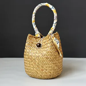 Close-up detail of a handmade seagrass woven bucket bag featuring a floral fabric handle.