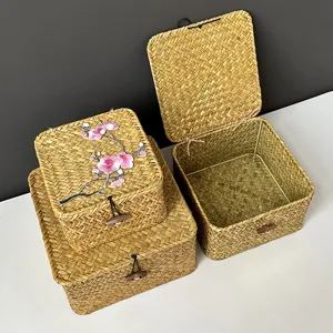 Detail der handgeflochtenen Stroh-Aufbewahrungsbox mit rosa Blumenstickerei