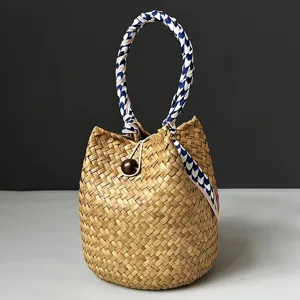 Detailed shot of a hand-woven seagrass bucket bag with a blue patterned scarf handle.