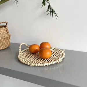 Gedetailleerd overzicht van een rond rotan serveerblad met handvatten en verse sinaasappels.