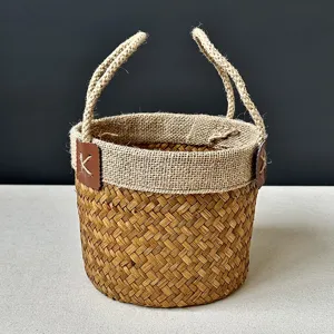 Close up detail of handmade natural seagrass woven storage basket with sturdy burlap handles.