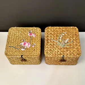 Nahaufnahme von zwei handgefertigten Stroh-Aufbewahrungsboxen mit Blumenstickerei.
