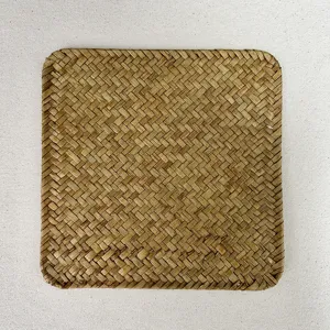 Close-up detail of natural hand-woven square seagrass placemat showing intricate straw texture.
