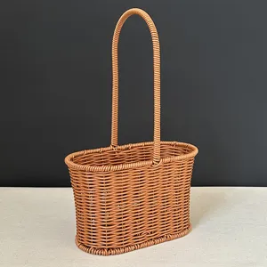Close-up view of the brown plastic rattan basket featuring a tall handle and oval base.