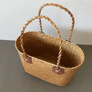 Detail of hand-woven seagrass basket with leather handle attachments and braided handles