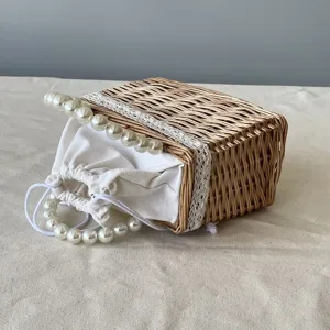 Macro detail of handwoven wicker gift basket featuring a pearl handle and lace trim.