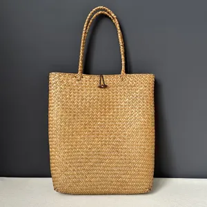 Detailed view of the woven straw bag handle and natural seagrass texture for summer trips.