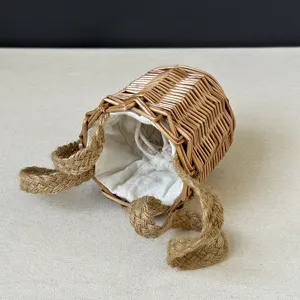 Mini cylindrical hand-woven straw basket with linen lining and jute handles for gifts.