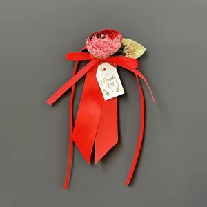 Dettaglio di un nastro rosso per pacco regalo con fiore di seta e tag Thank You