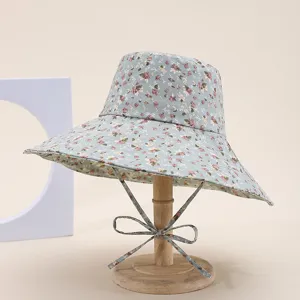 Detailed view of the floral bucket hat with adjustable ties and wide brim, light blue fabric.