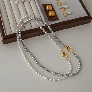 Detailopname van een grijze en witte parelketting met twee gouden ovale sluitingen