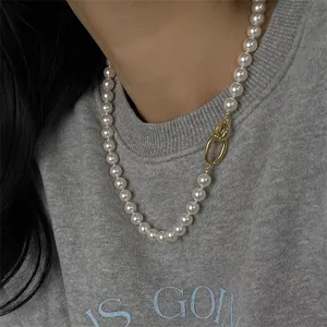 Detailopname van grijze parelketting met een stijlvolle gouden in elkaar grijpende sluiting.