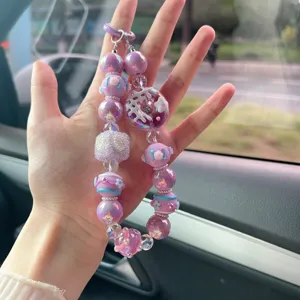 Dettaglio del ciondolo per telefono fatto a mano con ciambella viola e perle lucide