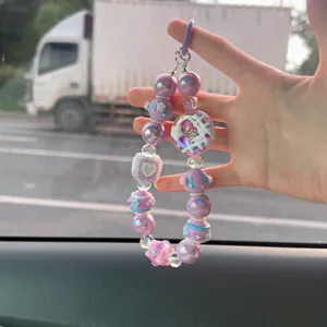 Ciondolo per telefono in perline viola con dettagli di design a ciambella e cuore.