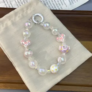Dettaglio di un ciondolo per telefono con perline colorate, cuori e ciambelle